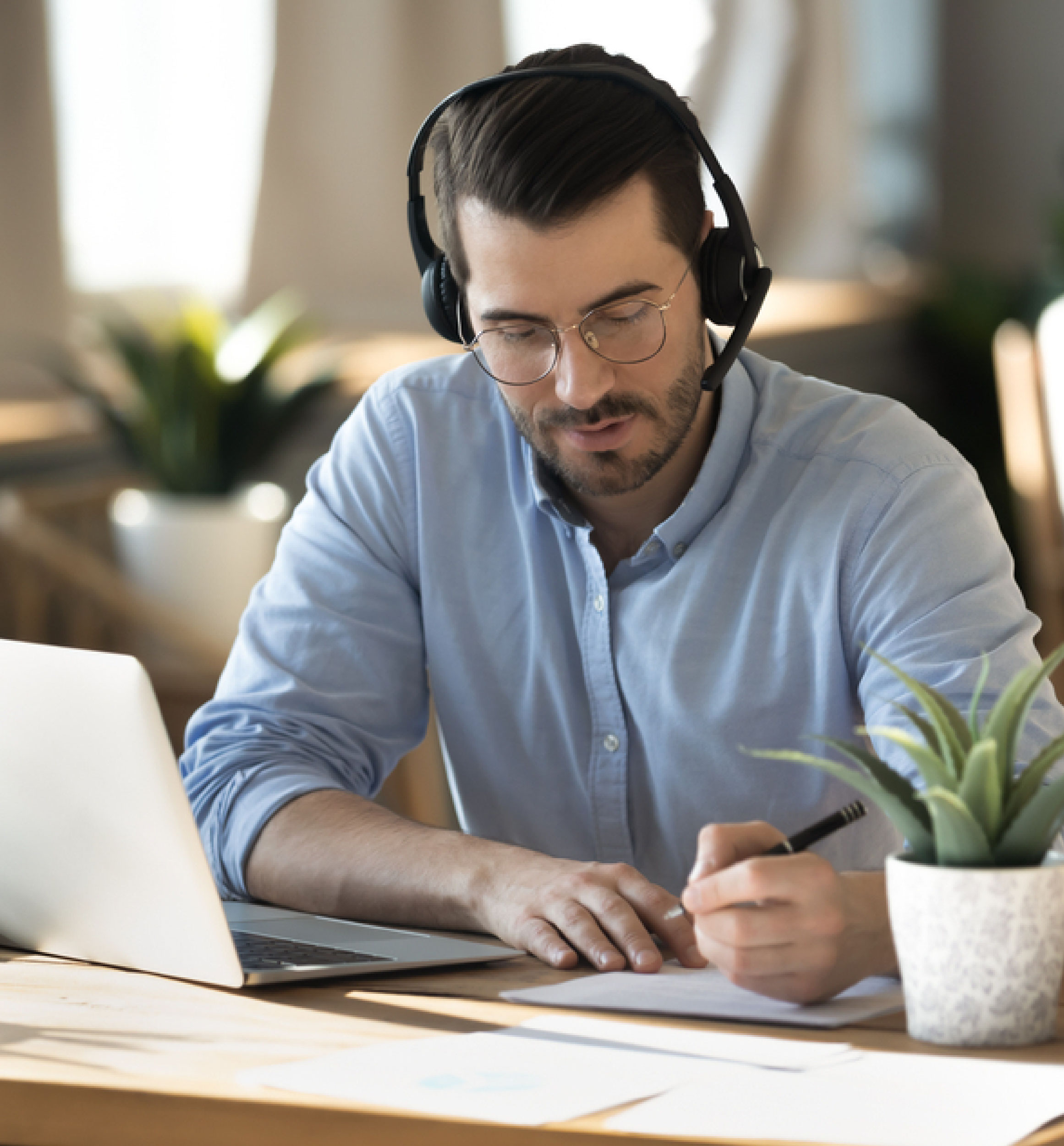 Man with headset writing notes online
